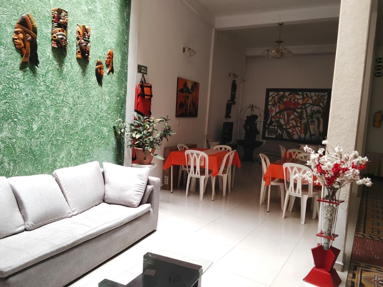 Sala con pared verde, máscaras indígenas y decoración amazónica